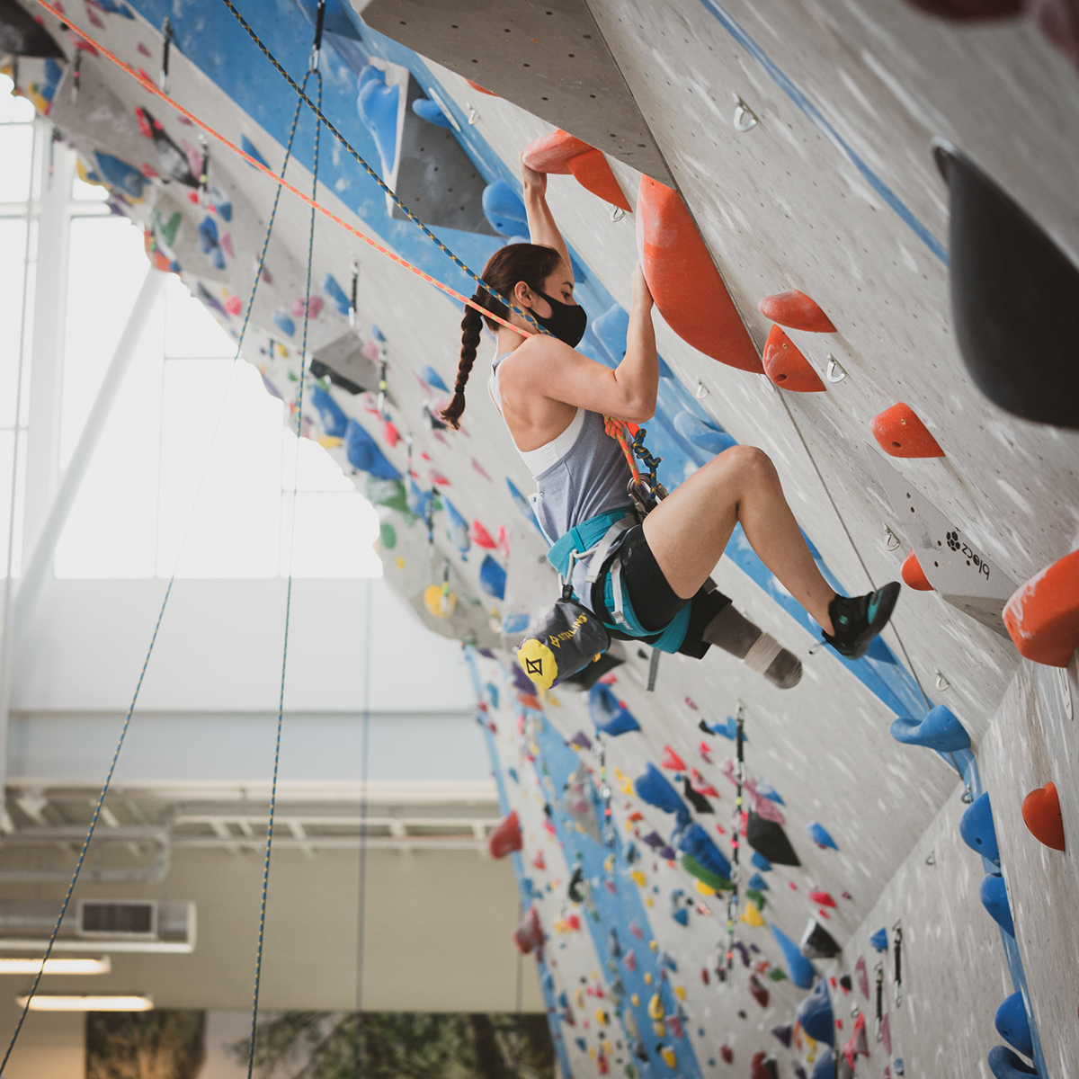 Paraclimbing athlete making their way up a climbing wall on top rope.