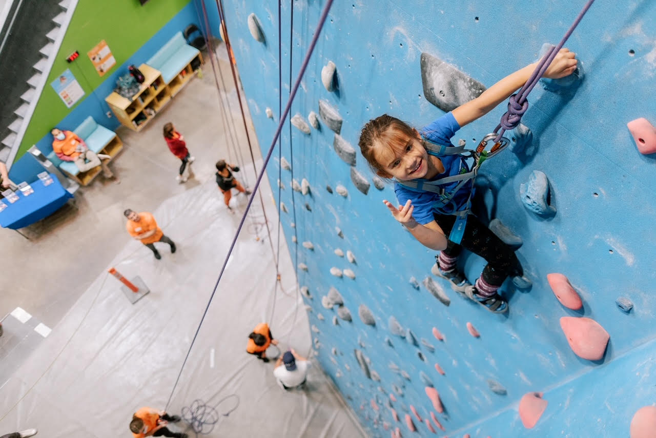 Youth scaling a climbing wall attached to a rope