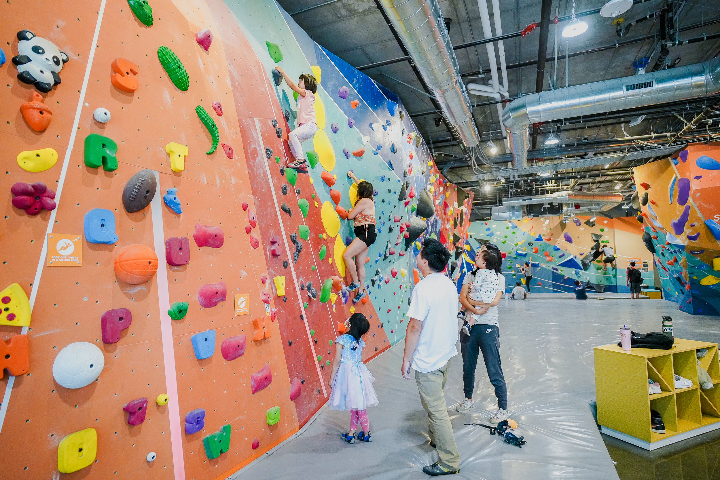 Family watching young people climb on a wall